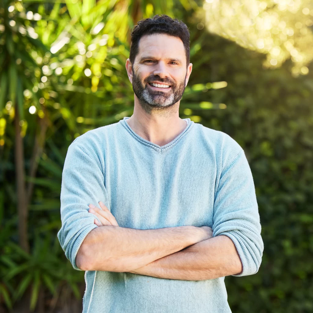 smiling-man-poses-in-front-of-greenery-2026-03-25-02-22-52-utc