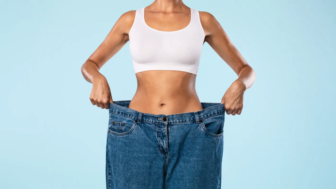 woman-holding-oversized-jeans-after-weight-loss-2026-03-24-02-19-43-utc